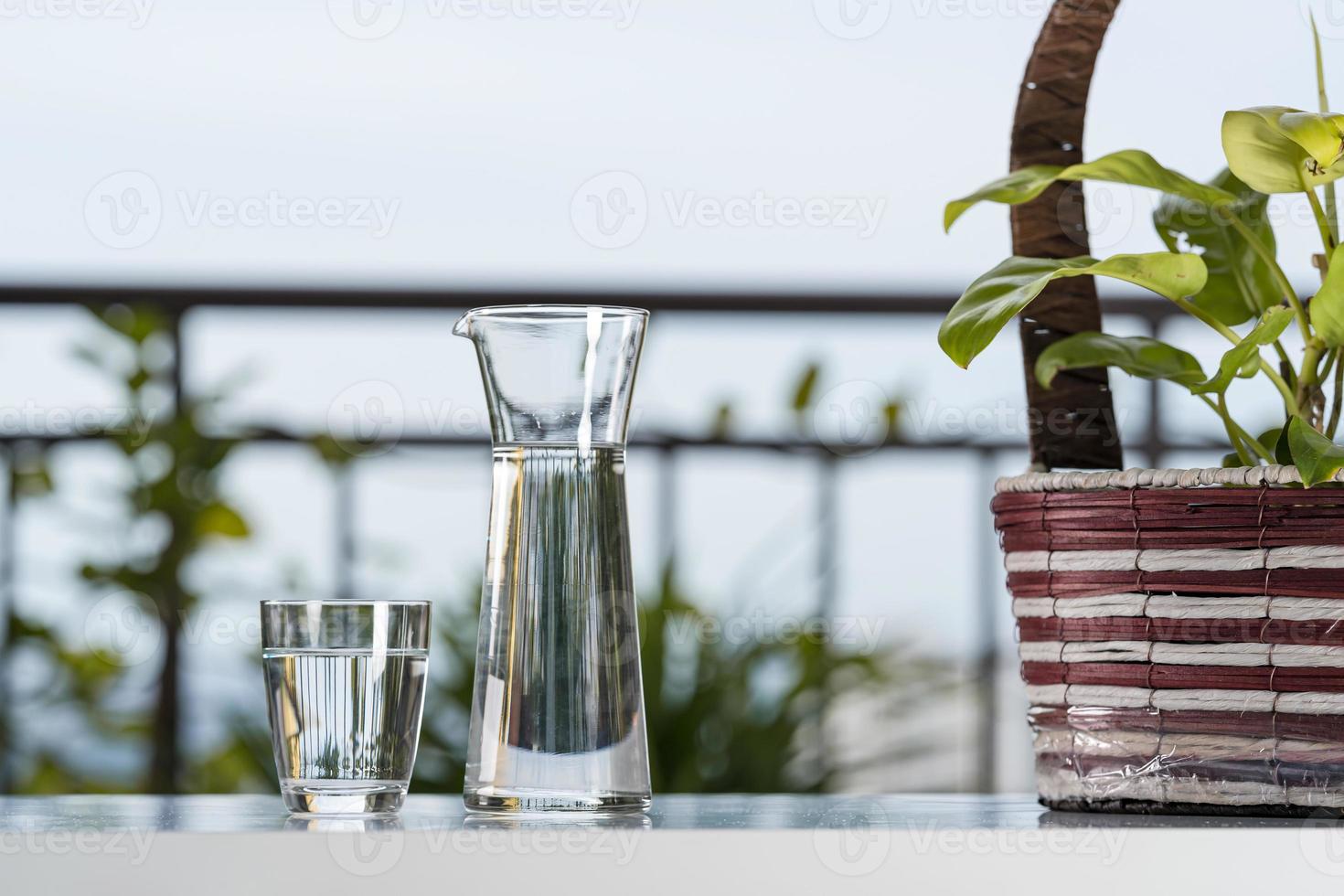 drick vattenglaskanna med glas på bordet i trädgårdshemmet foto