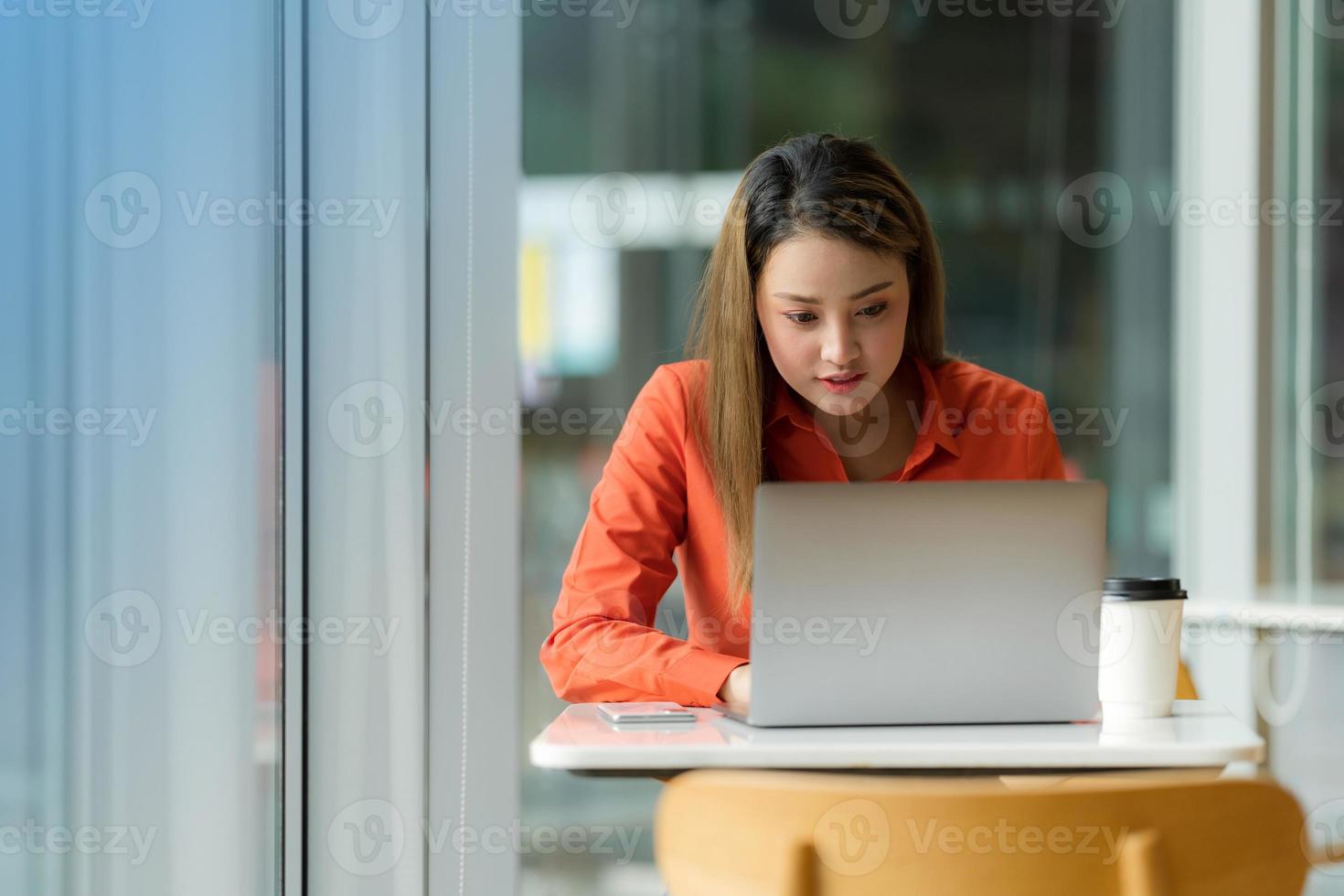 vacker ung kvinna med laptop sitter på ett kafé foto