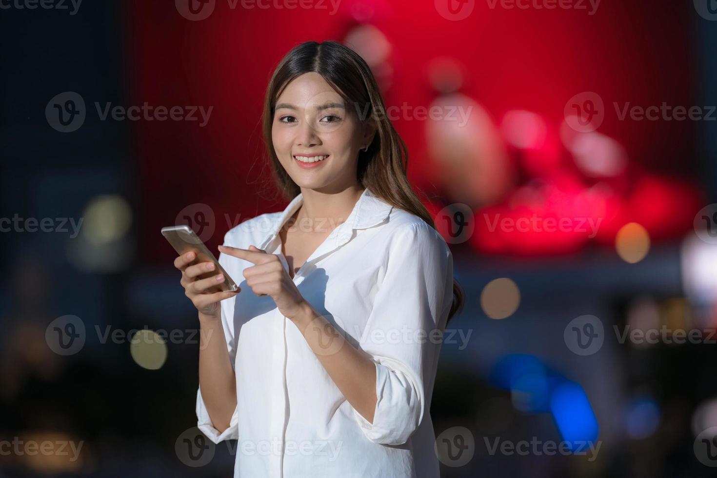 utomhus porträtt av ung kvinna med smiley ansikte med en telefon promenader i en stad foto