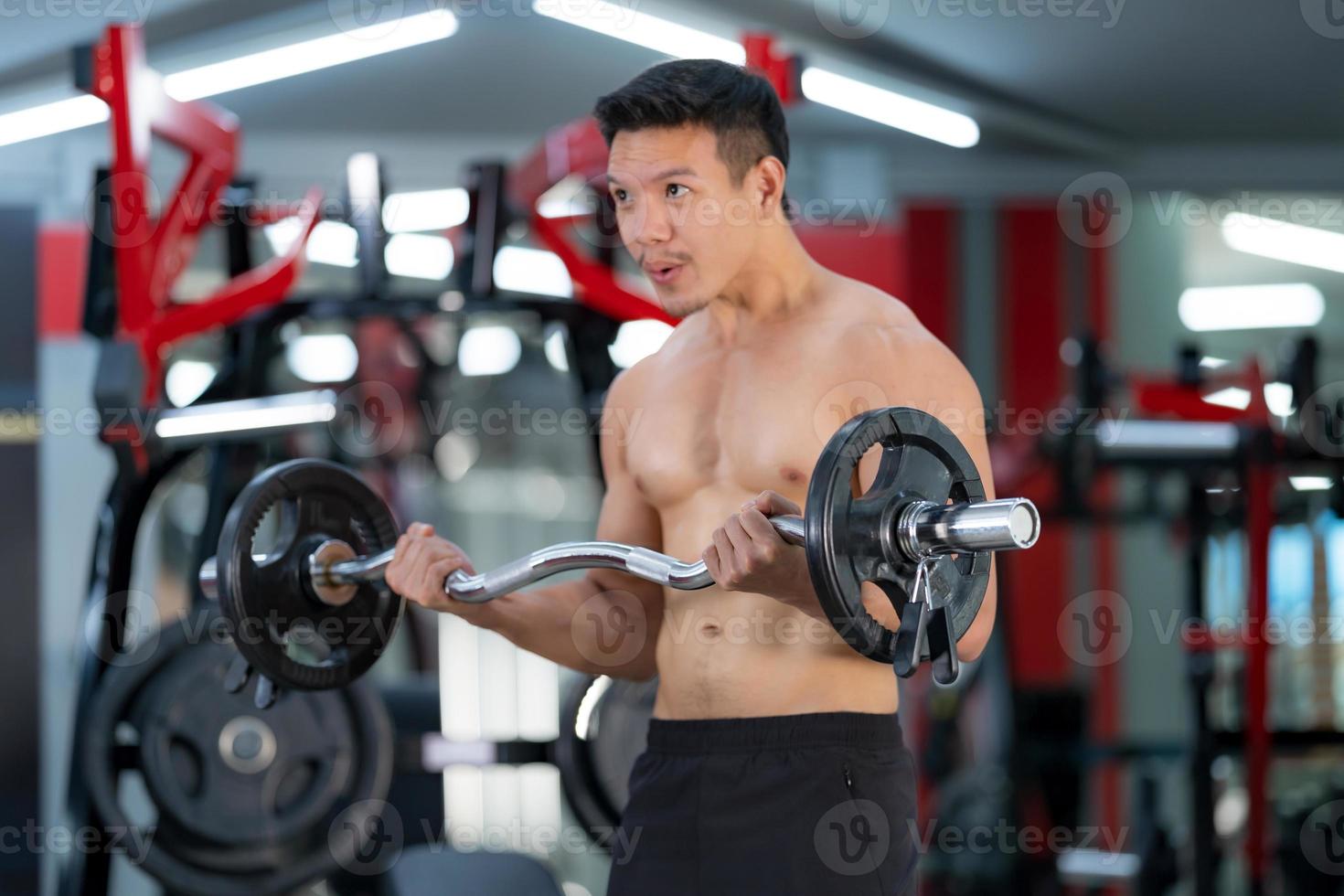 sportig man tränar med en tung skivstång på gymmet foto