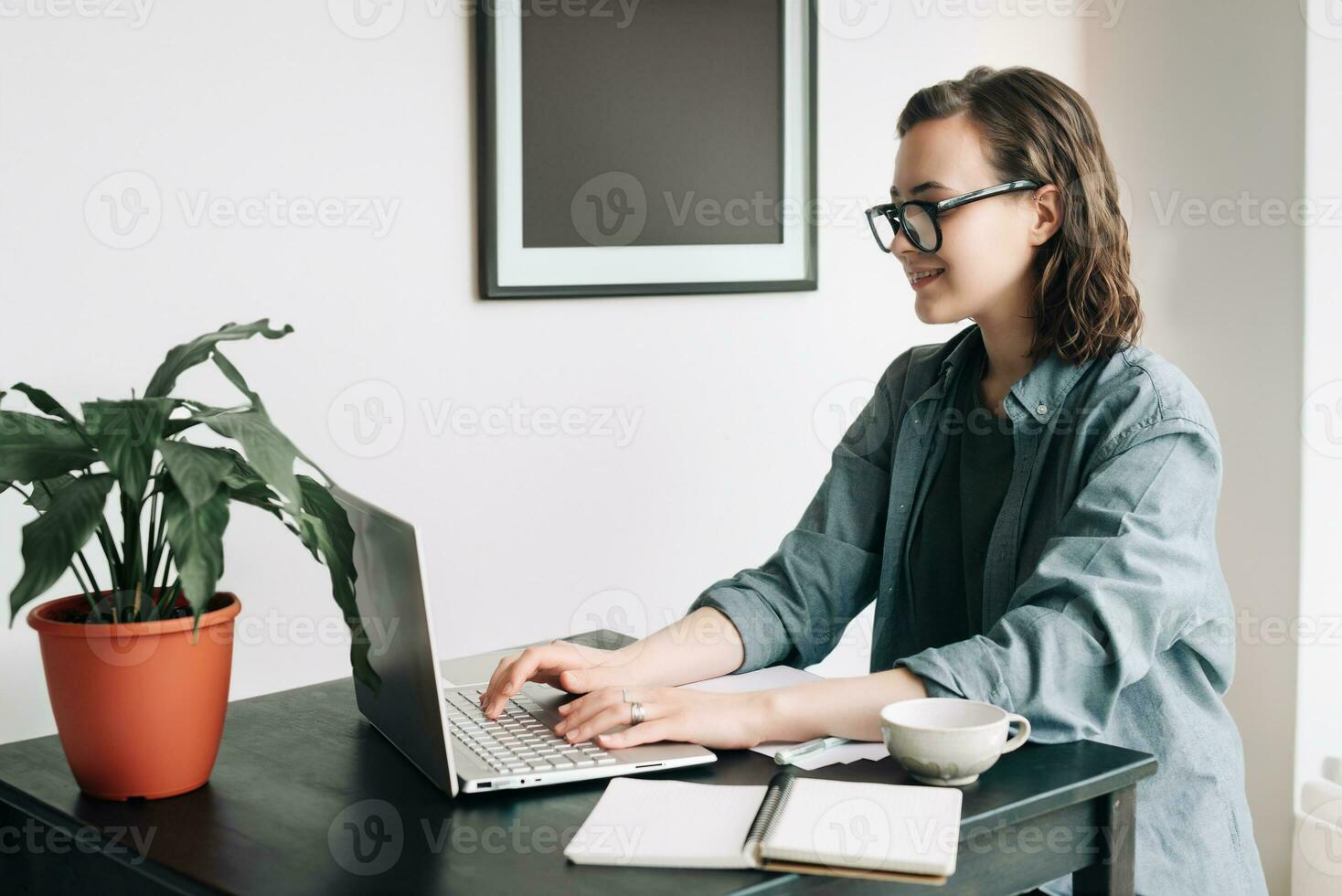 professionell ung kvinna använder sig av bärbar dator i kontor. studerande flicka arbetssätt avlägset från Hem. arbete eller studie från Hem, frilans, företag, och livsstil begrepp. teknologi, produktivitet, utbildning foto