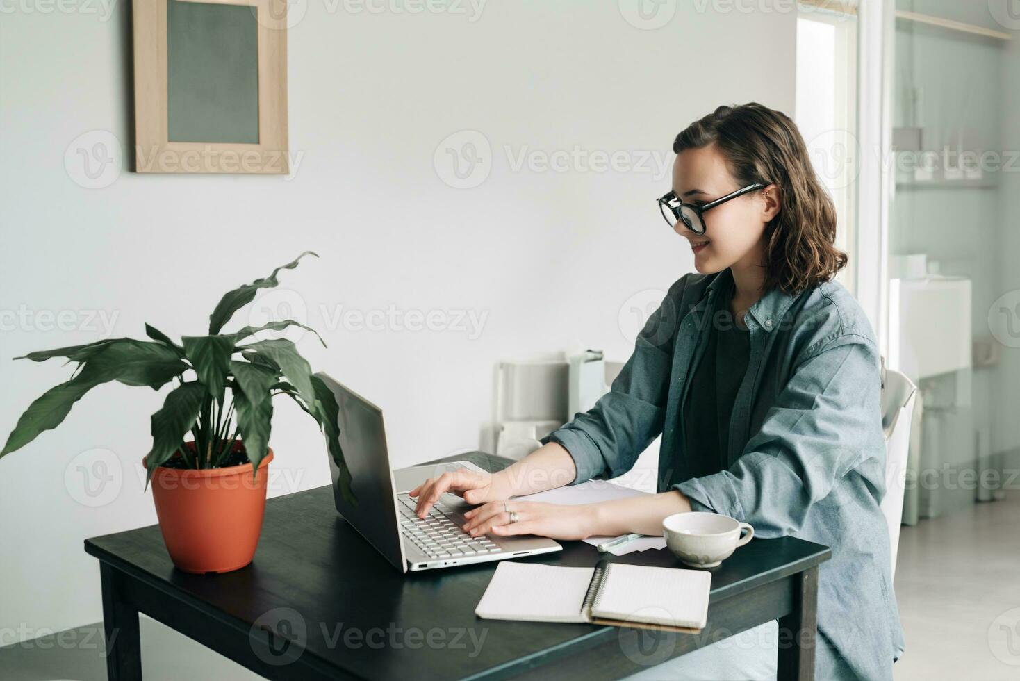 ung kvinna arbetssätt på bärbar dator i modern kontor. studerande flicka studerar eller frilansar från Hem. arbeta hemifrån, företag, och livsstil begrepp. teknologi, produktivitet, utbildning, och avlägsen arbete foto