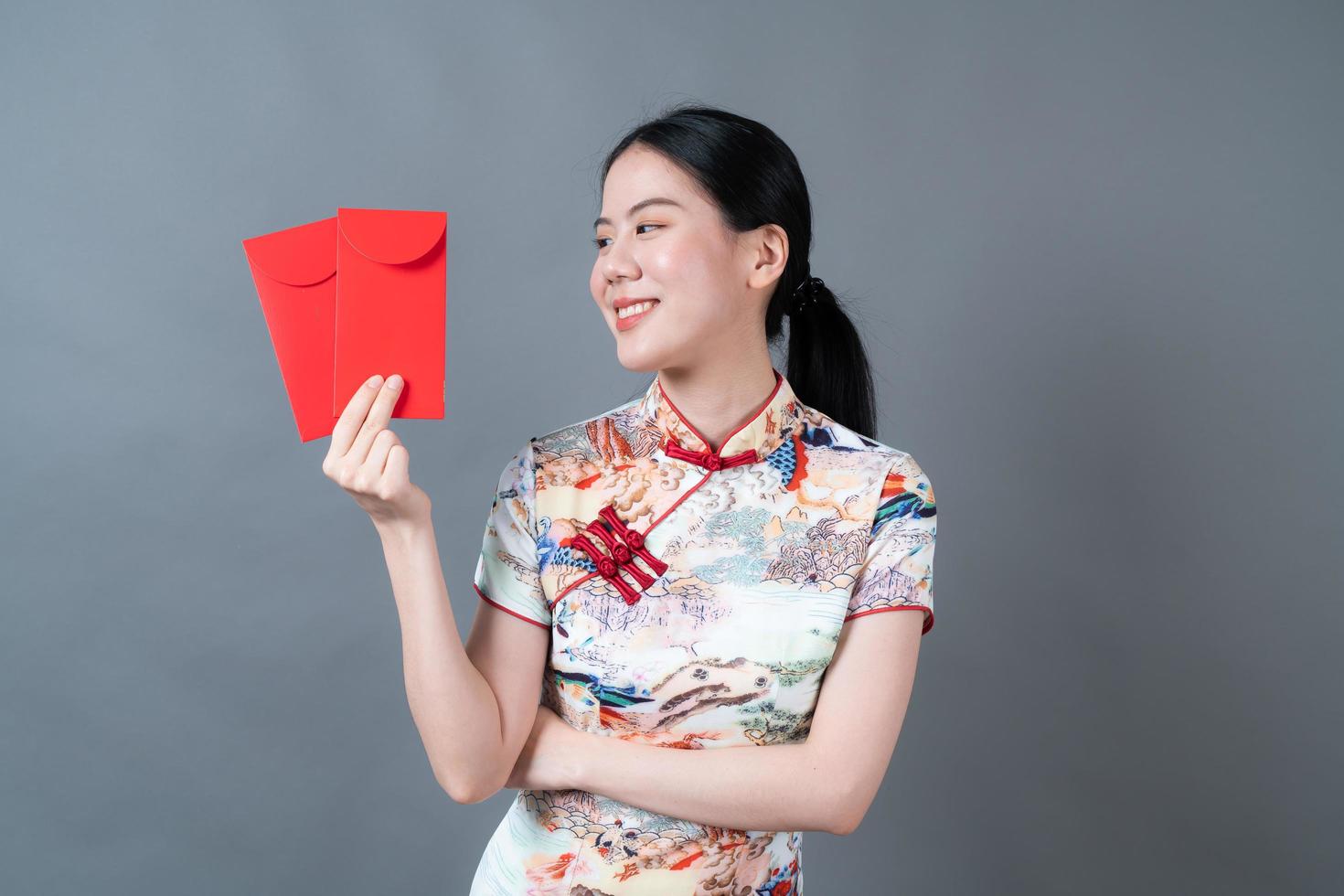 asiatisk kvinna bär kinesisk traditionell klänning med rött kuvert eller rött paket foto