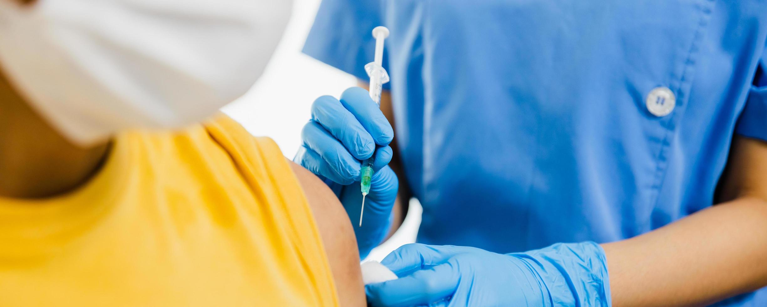 närbild på kvinnlig läkare som håller sprutan och använder bomull innan du injicerar patienten i medicinsk mask. covid-19 eller koronavirusvaccin foto