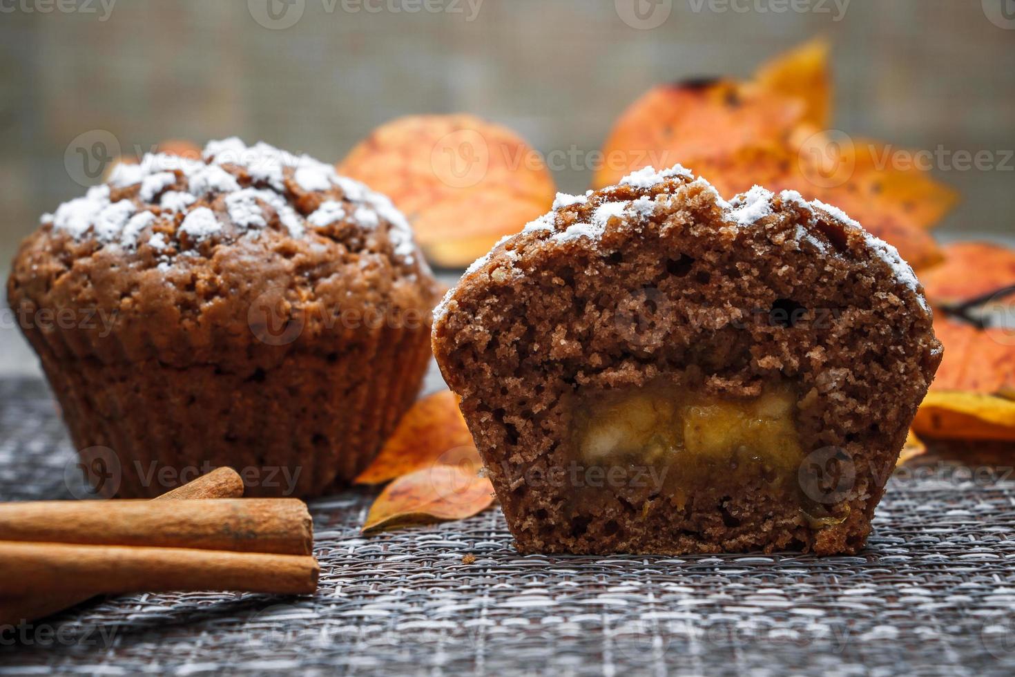 chokladmuffins med äppelfyllning på en bakgrund av höstlöv och kanel foto
