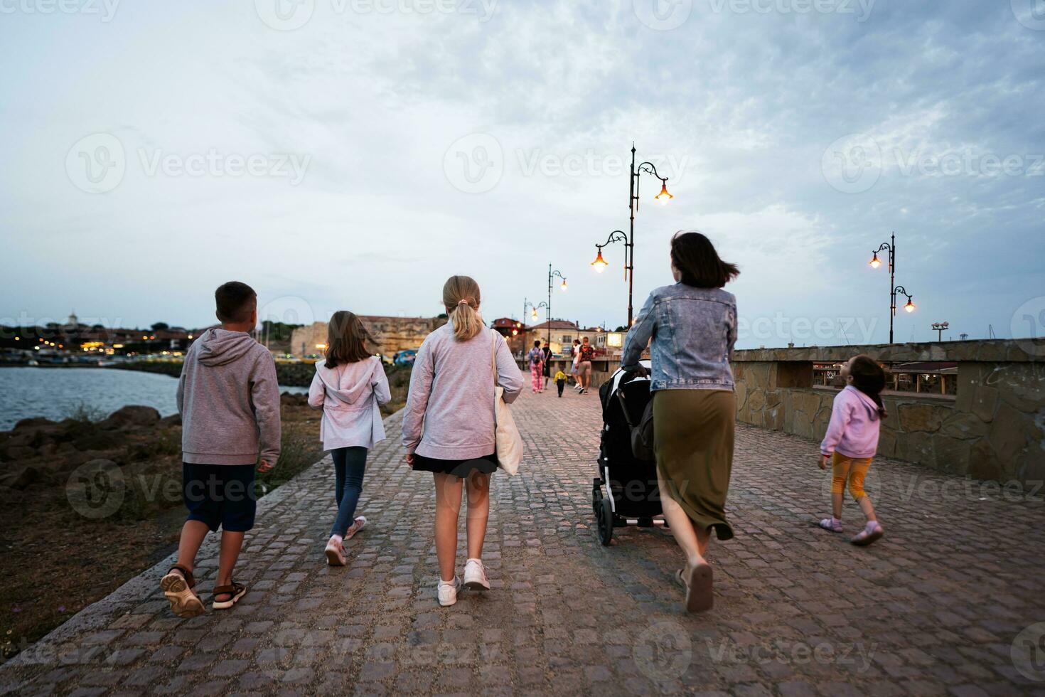 grupp av barn med mor gående på de promenad i de kväll nessebar, bulgarien. foto