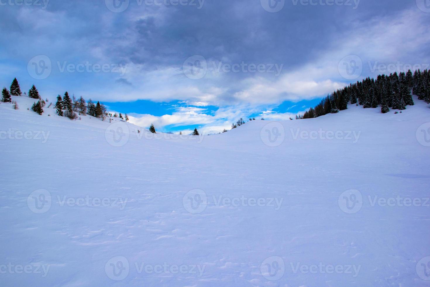 snöig kulle och blå himmel med moln foto