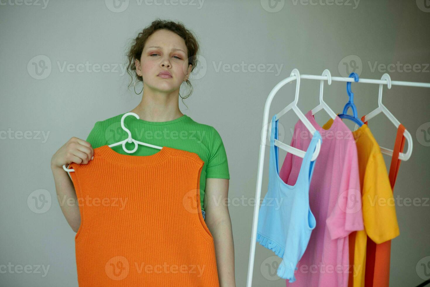 porträtt av en ung kvinna strykning kläder på en galge garderob beskurna se oförändrad foto