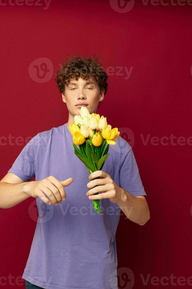 söt tonåring innehav en gul bukett av blommor lila t-tröjor isolerat bakgrund oförändrad foto