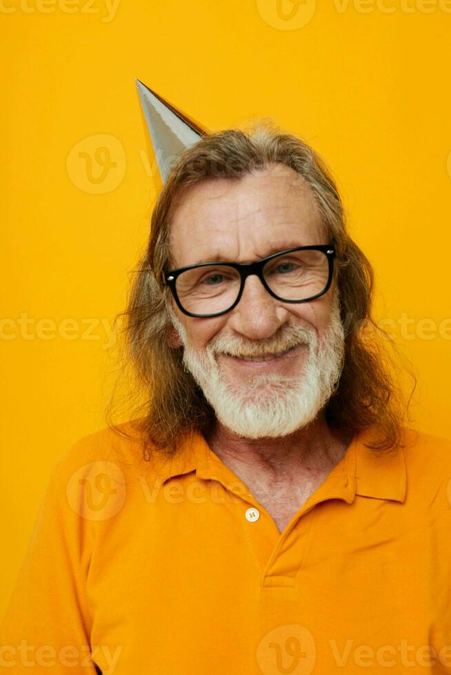 äldre skäggig man bär glasögon med en keps på hans huvud gul bakgrund foto