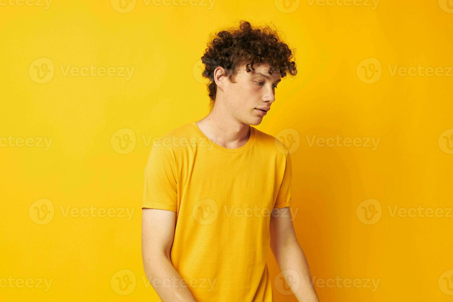 ung lockigt hår man bär eleganta gul t-shirt Framställ livsstil oförändrad foto