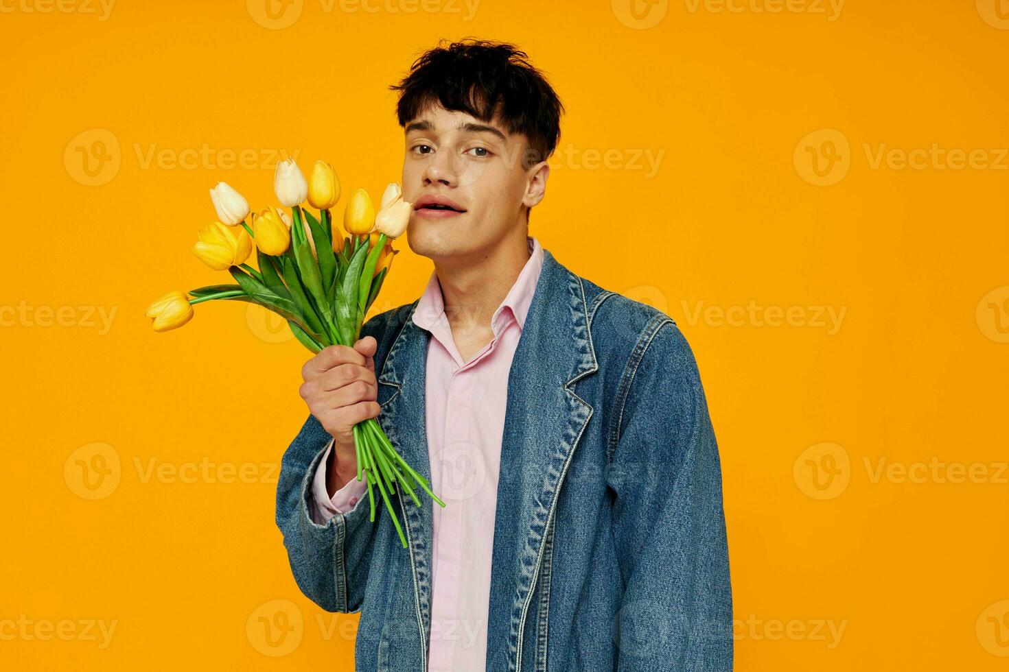 ung kille i denim jacka med en bukett av blommor Framställ roman foto