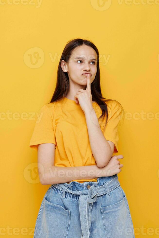 optimistisk ung kvinna i en gul t-shirt känslor sommar stil gul bakgrund foto