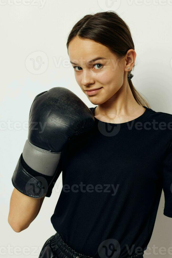 Foto Söt flicka i boxning handskar i svart byxor och en t-shirt kondition Träning