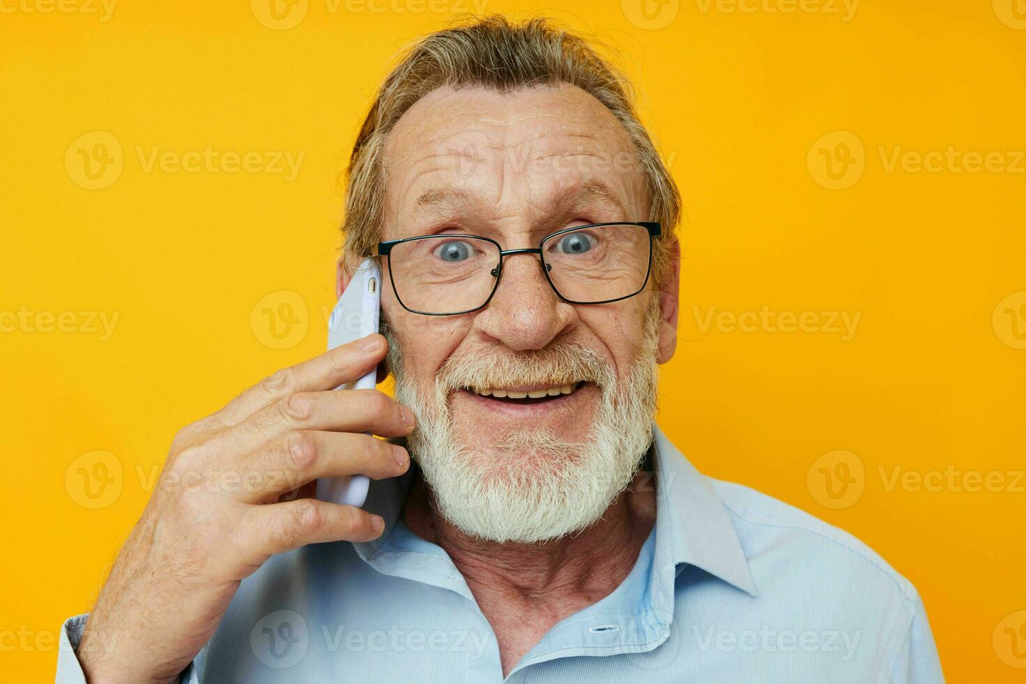 Foto av pensionerad gammal man grå skägg med glasögon talande på de telefon gul bakgrund