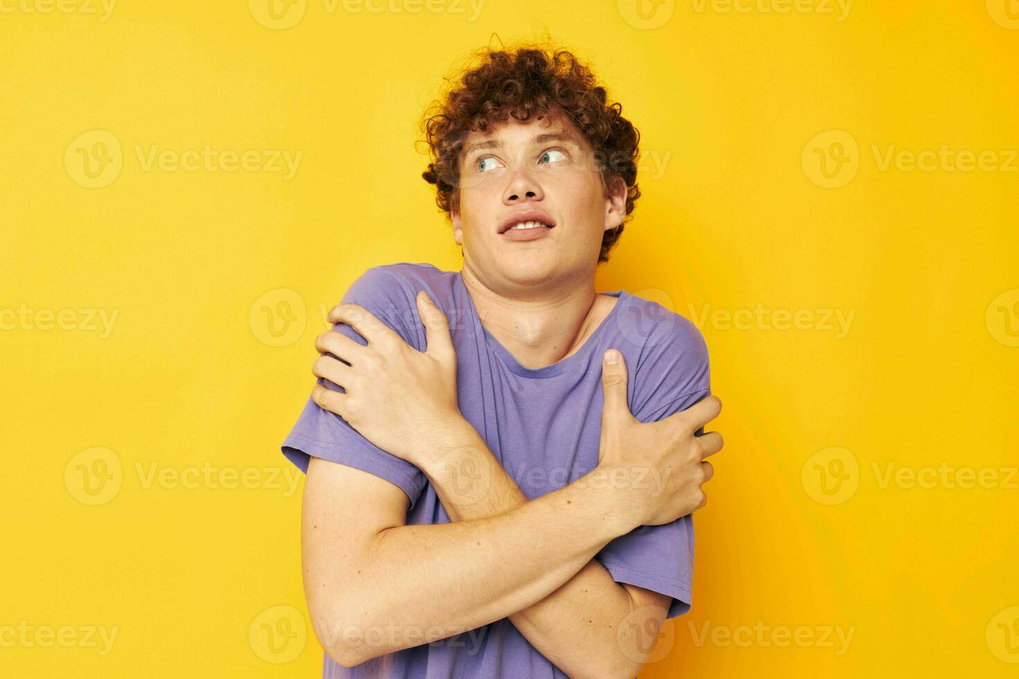 kille med lockigt hår i lila t-tröjor studio gul bakgrund foto