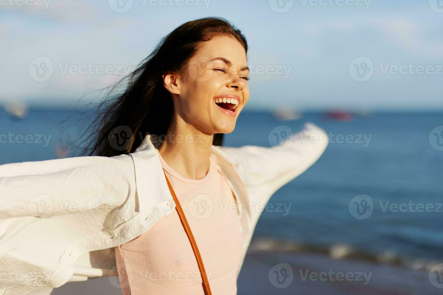 kvinna leende med tänder frihet på semester gående på de strand förbi de hav i bali solnedgång, Lycklig resa och avslappning, solnedgång ljus, flygande hår, de begrepp av förändra och emotionell hälsa foto