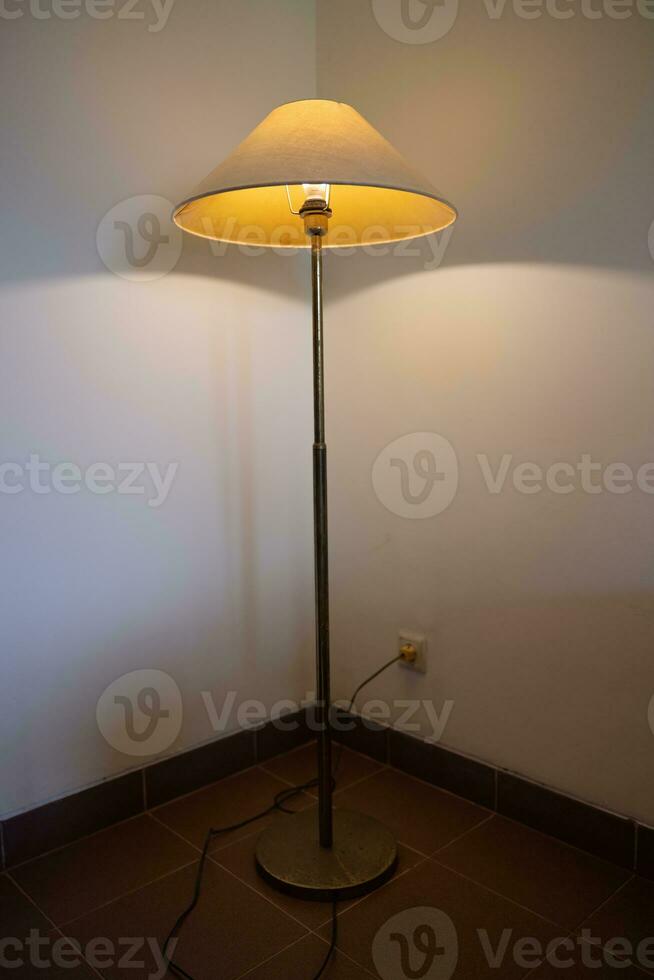 interiör med golv lampa och glöd Glödlampa i de mörk på natt, ett lampa i de hörn mot en golv lampa vägg. foto