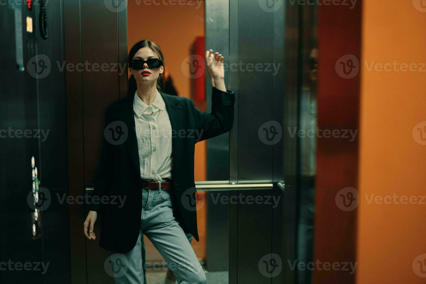 eleganta kvinna i svart jacka och solglasögon Framställ i hiss, mode modell, mörk filmiska ljus och Färg, glamour årgång foto