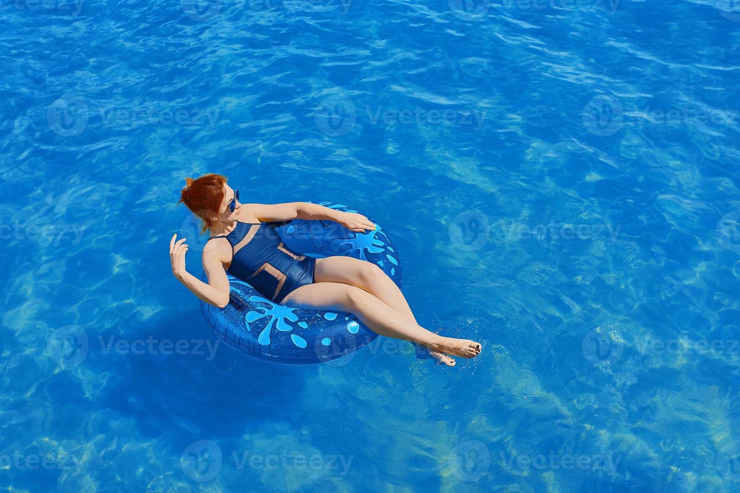 vacker ung kvinna koppla av på uppblåsbar ring i havsvatten foto