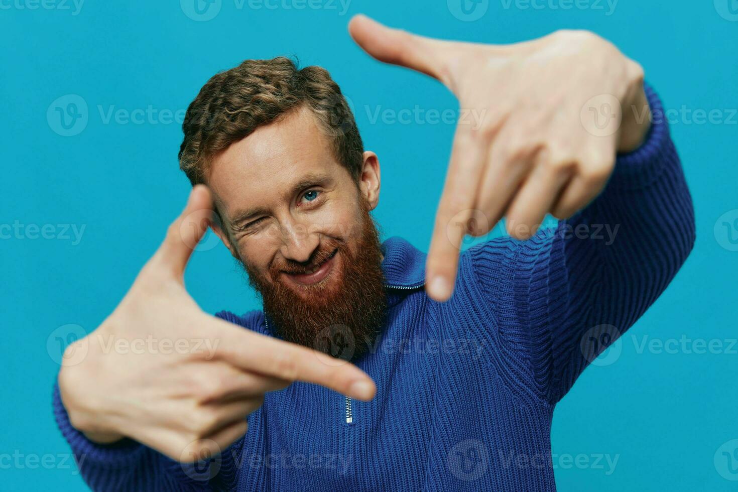 porträtt av en man i en Tröja leende och lycka, hand tecken och symboler, på en blå bakgrund. livsstil positiv, kopia plats. foto