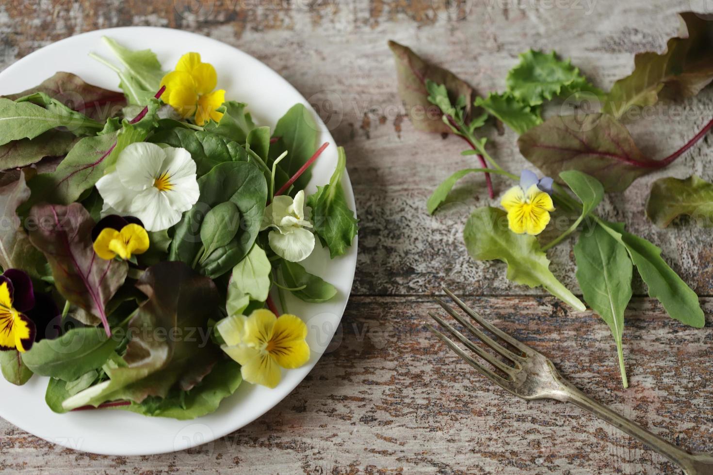 blandning av sallad med blommor på en vit tallrik foto