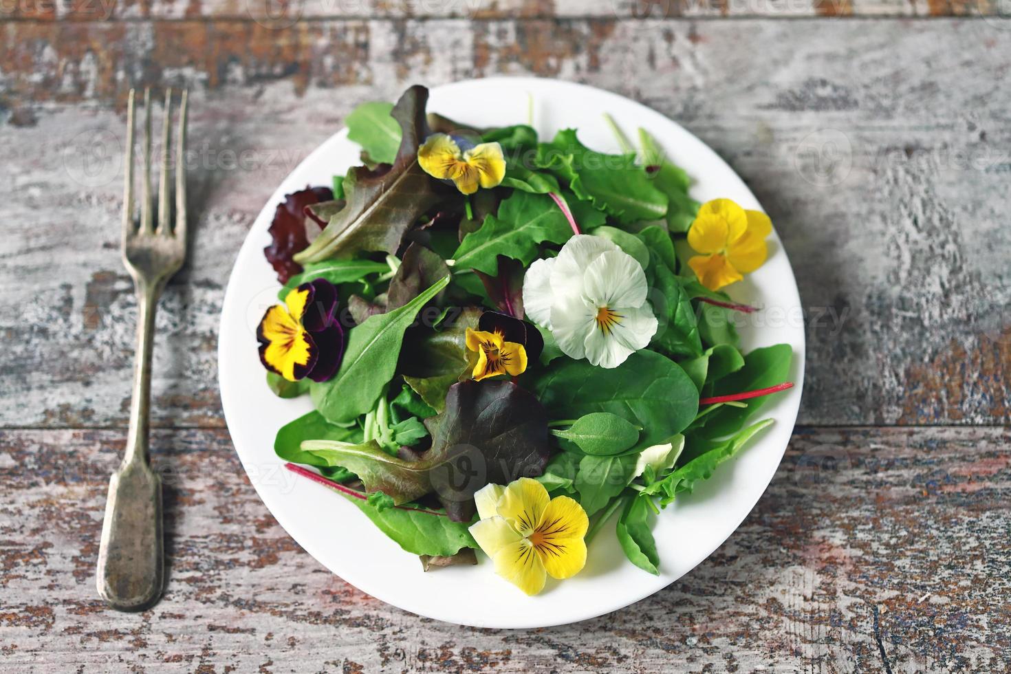 blandning av sallad med blommor på en vit tallrik foto