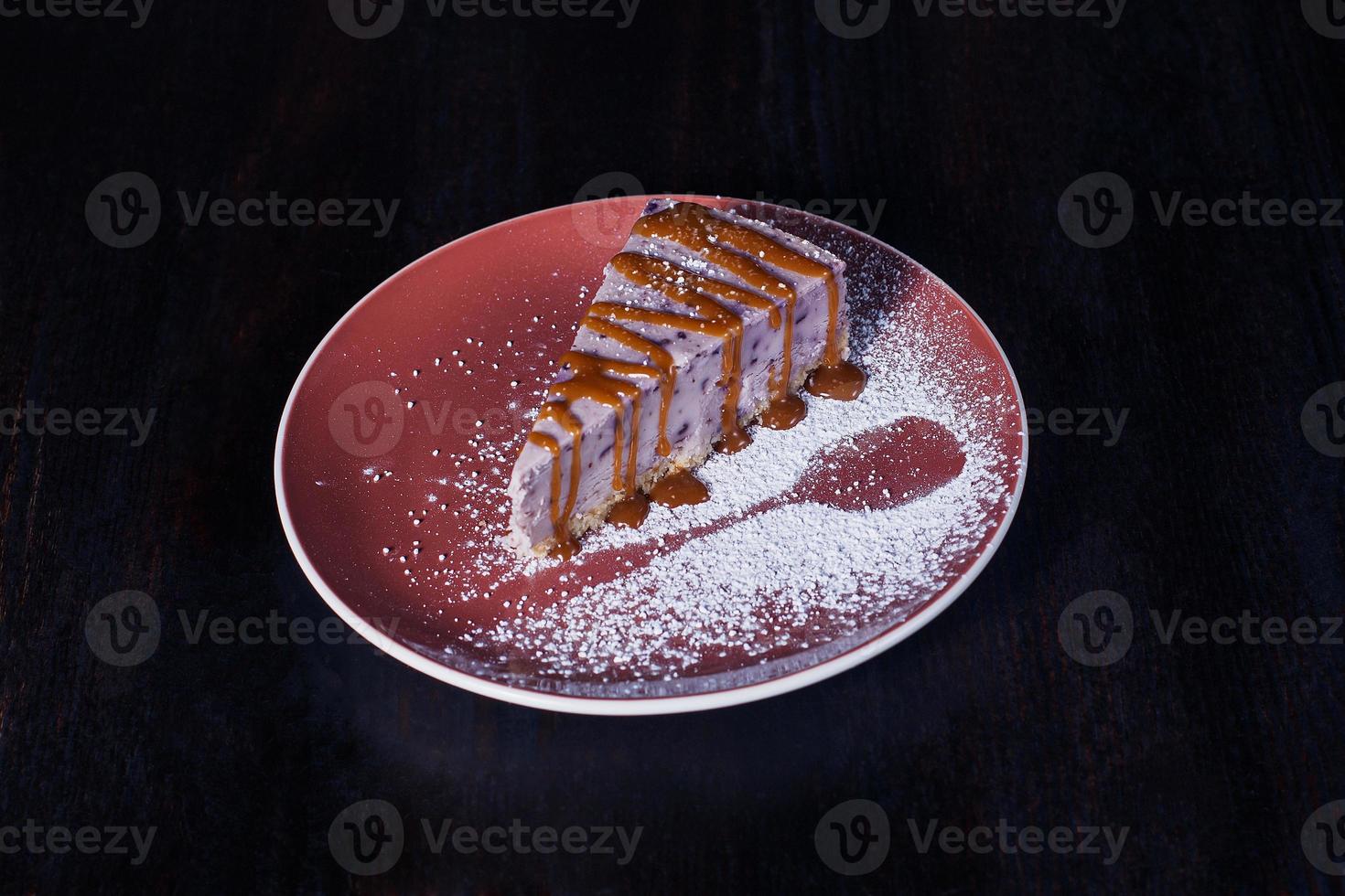 söt dessertkaka på en tallrik, härlig servering, mörk bakgrund foto