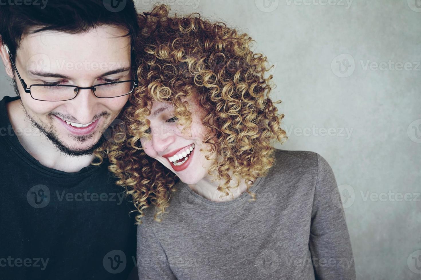 porträtt av ett naturligt kaukasiskt par ung kvinna med lockigt blont hår och man som delar tid tillsammans och ler medan de blir roliga foto