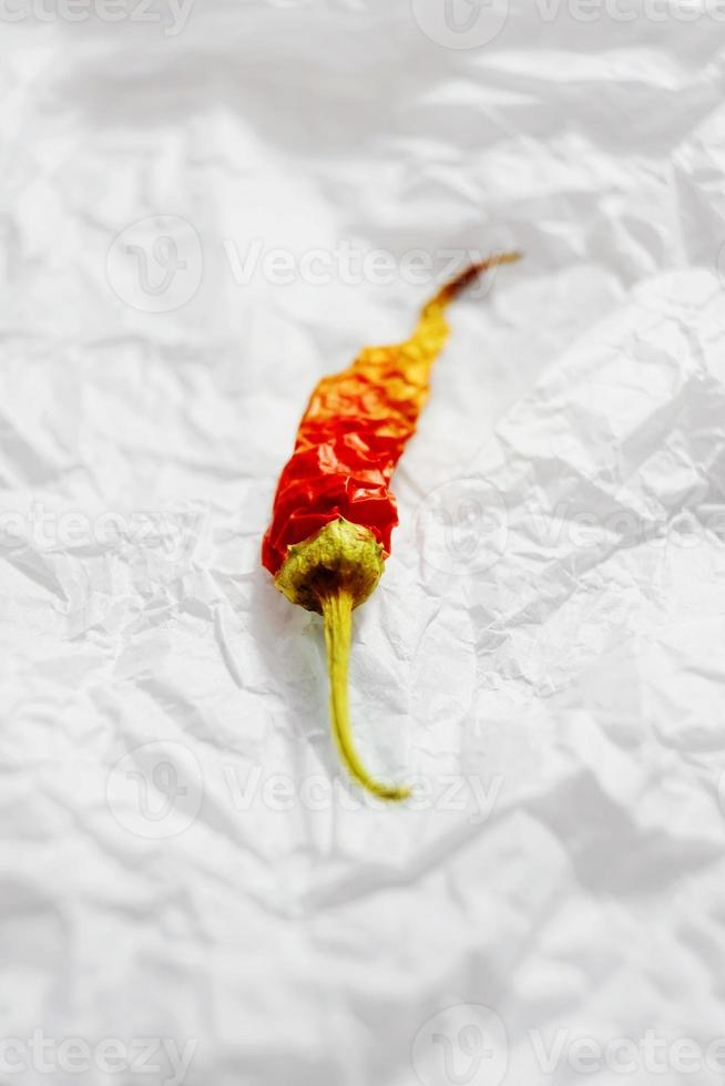 ett fantastiskt och vackert makro av en röd och gul chili eller peppar på ett vitt skrynkligt papper eller tyg foto