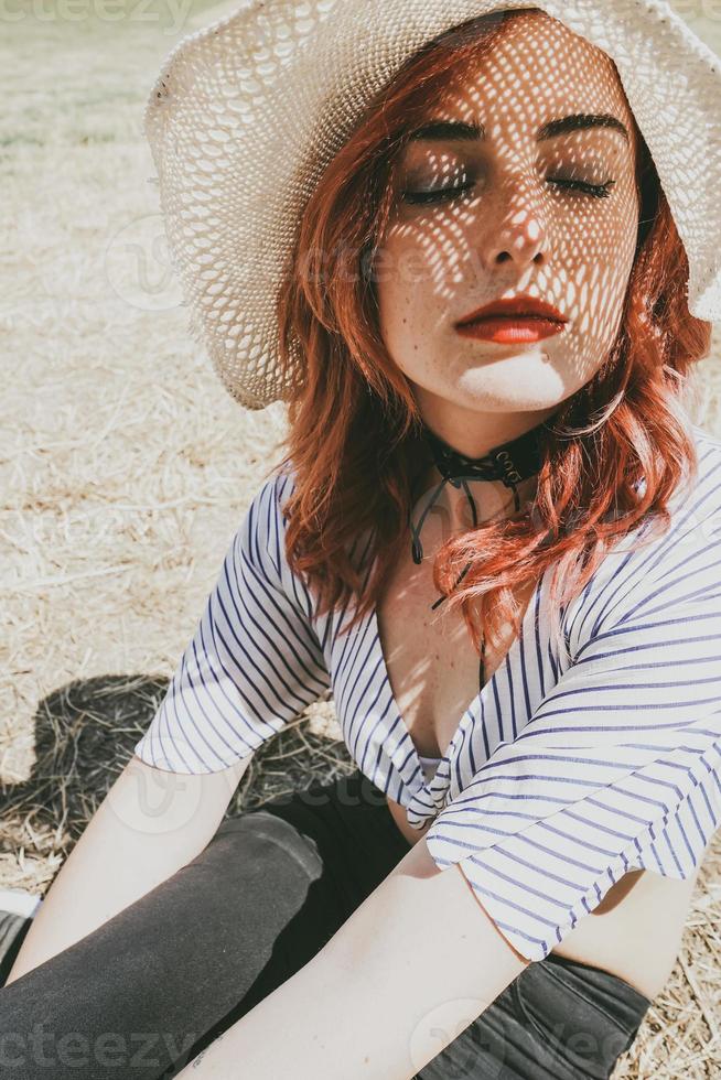 rödhårig modell som skyddar sig mot solen med en hatt på sommaren foto