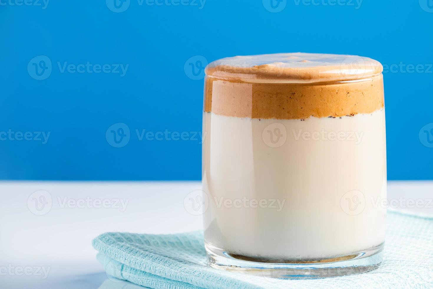 dalgona kaffe på en blå bakgrund modetrend drink av mjölk och söt vispad skum foto