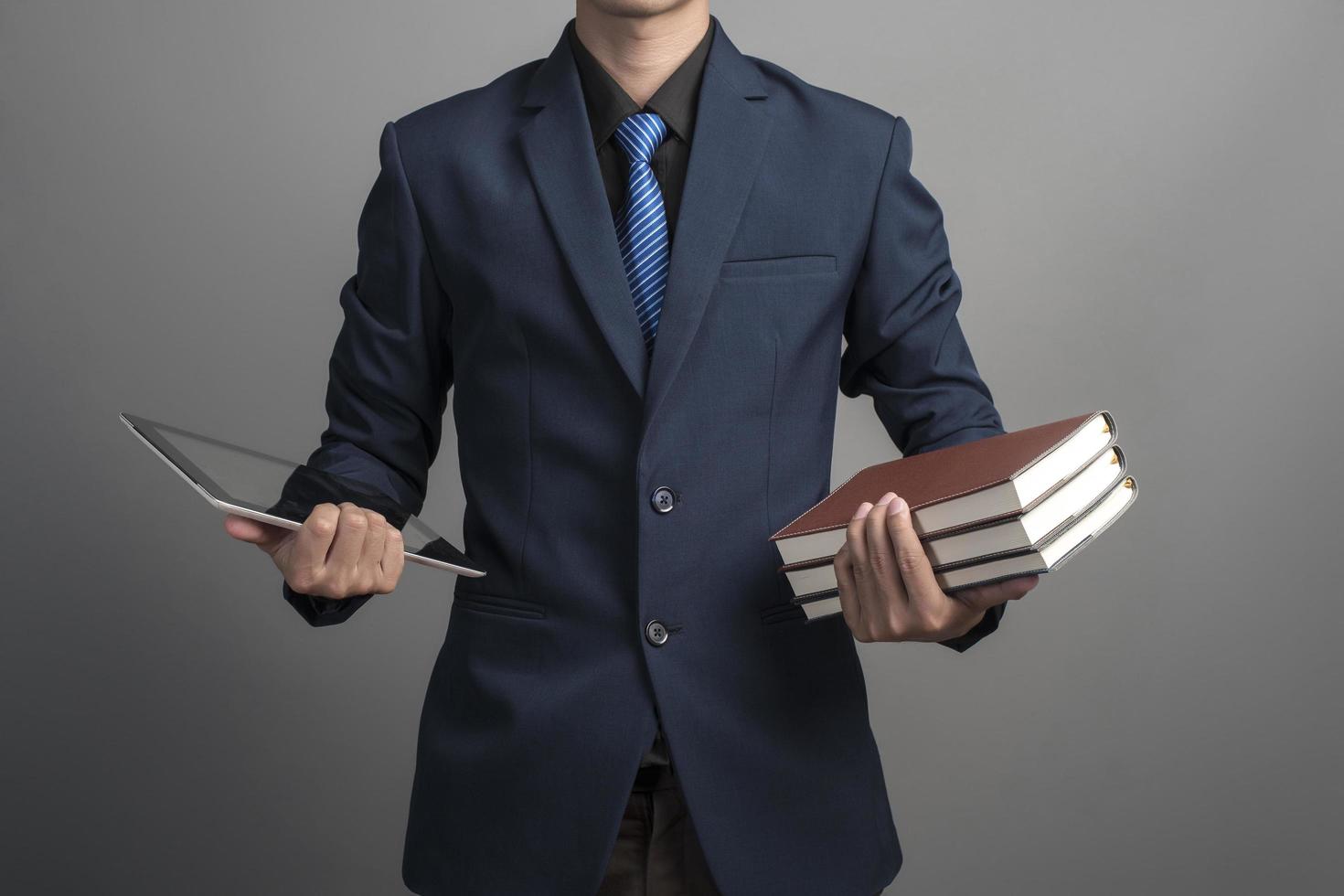 närbild av affärsmannen i blå kostym håller böcker på grå bakgrund foto
