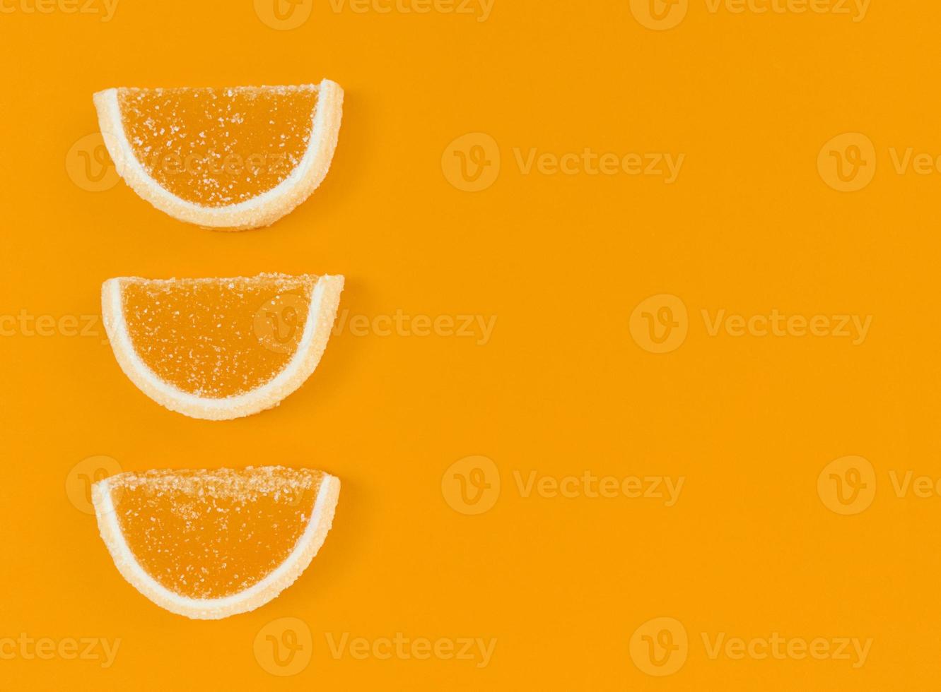 marmelad apelsinskivor i socker på orange färgbakgrund med kopieringsutrymme. foto