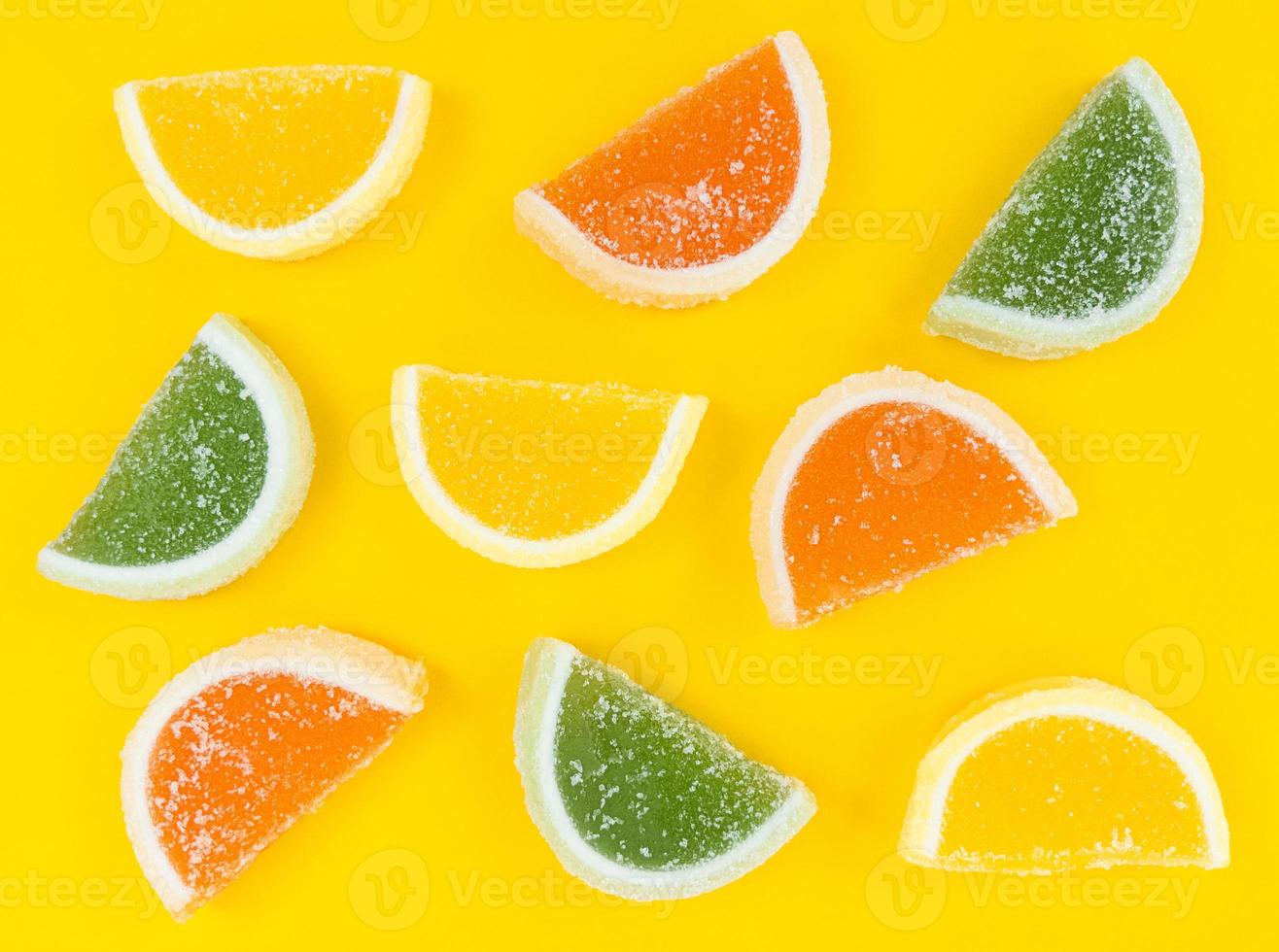 mångfärgade skivor av marmeladcitrus i socker på gul bakgrund. foto