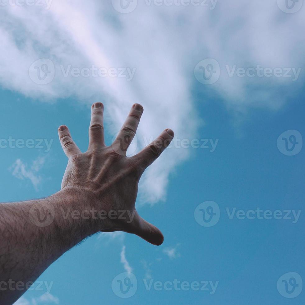 handen uppåt och når den blå himlen foto