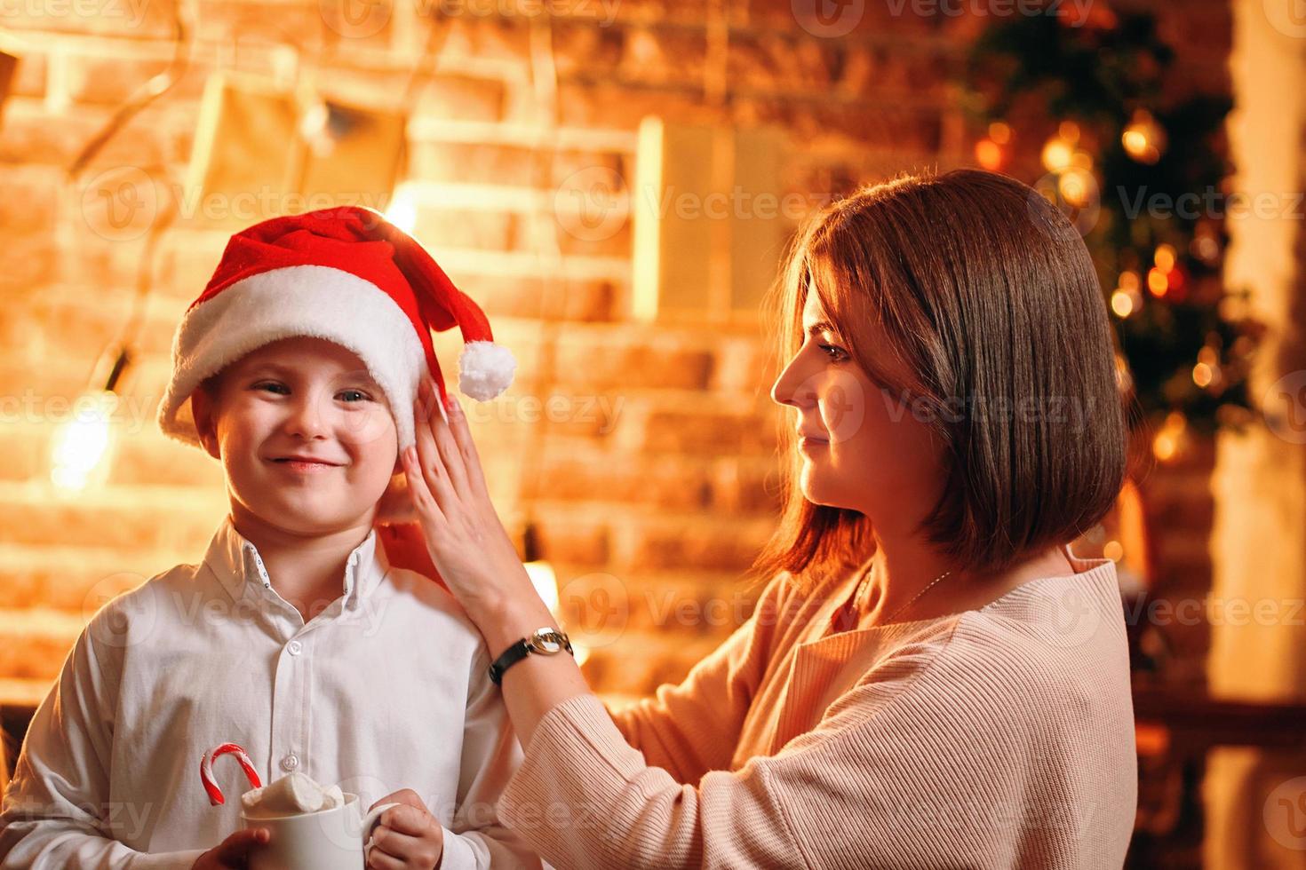 mamma sätter jultomten julhatt på sitt barn foto