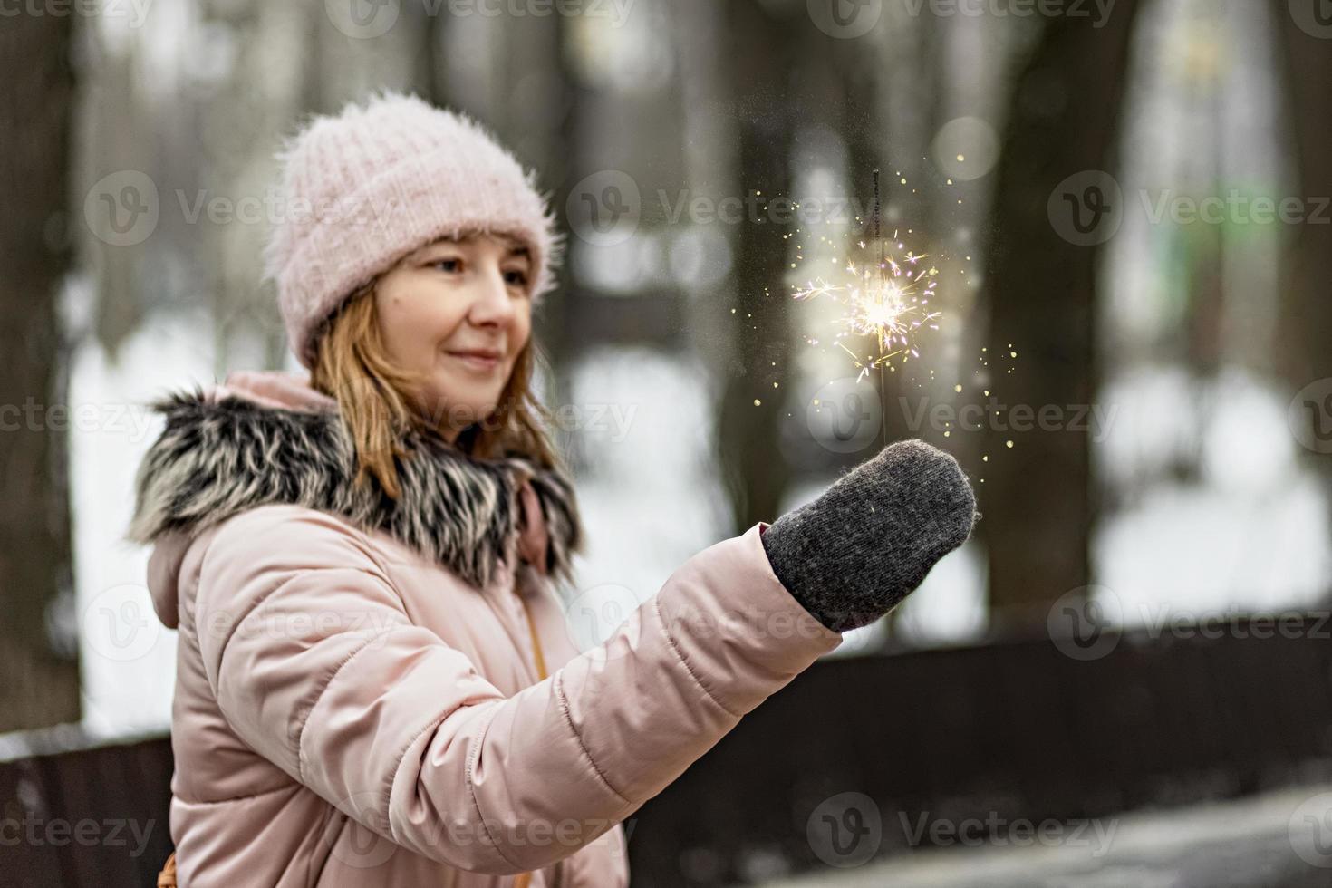 julbelysning är ljusa stänk som brinner i händerna på en suddig glad kvinna i parken. tomtebloss. känslor, nyårsstämning. vintersemester foto