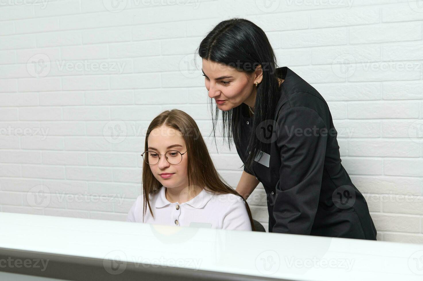 ung självsäker skön kvinna läkare schemaläggning utnämning, stående nära receptionist förbi reception skrivbord i klinik foto