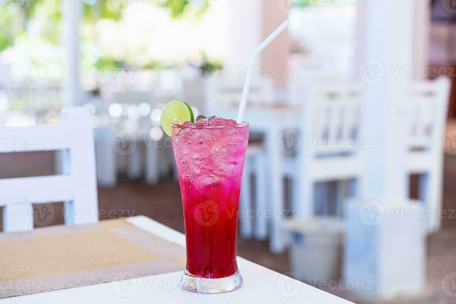 kall röd juice med iced Valp och en skiva av citron- på topp av glas på tabell på restaurang. glas av alkoholhaltig uppfriskande dryck dekorerad citron- skiva. strand bar, sommar hav tillflykt begrepp. foto