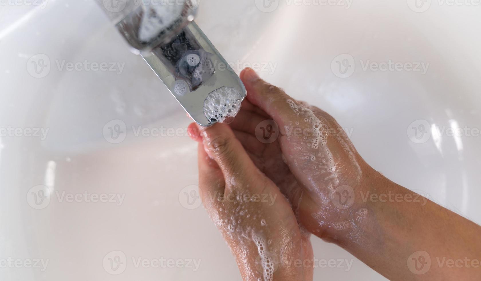 närbild av en man som tvättar händerna med tvål i diskbänken foto