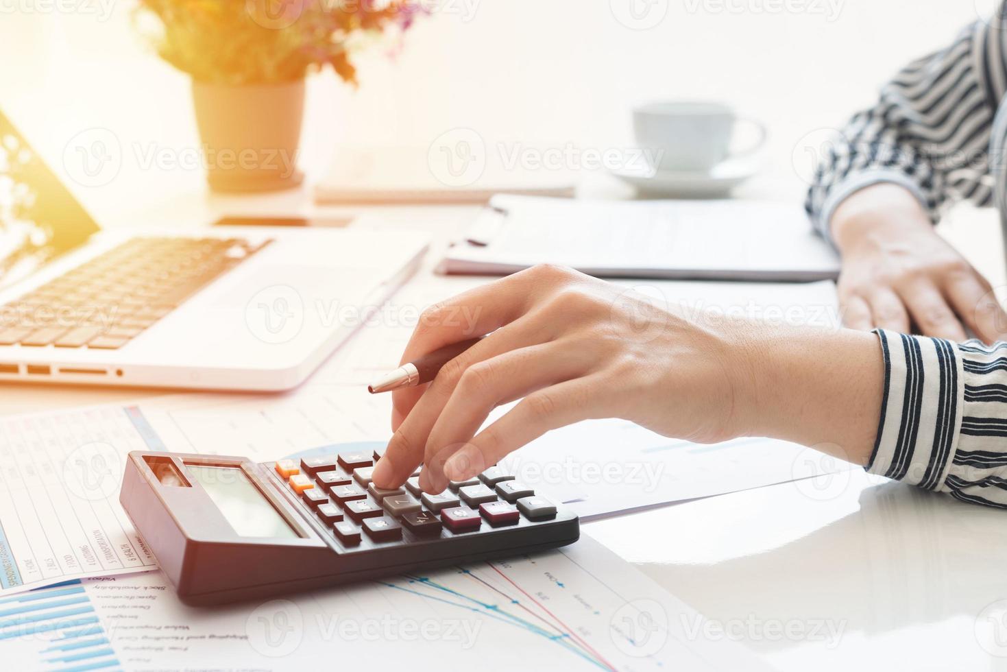 affärskvinna som använder en miniräknare och skriver anteckningar. skatter, besparingar, ekonomi och ekonomikoncept foto