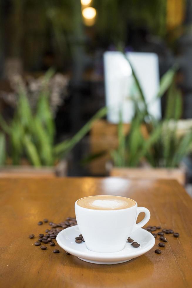 kaffekopp och kaffebönor på bordet på ett träskrivbord foto