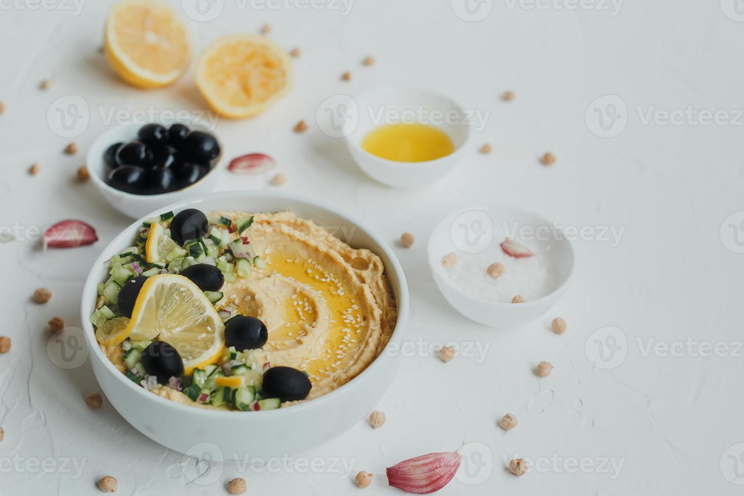 hummus från kikärter, med olivolja, oliver, citron, vitlök, sesamfrön, lök och gurkor. foto