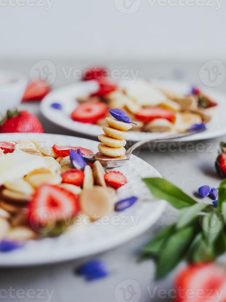 pannkakaflingor, trendig mat. mini spannmålspannkakor med smör, honung och jordgubbar. foto