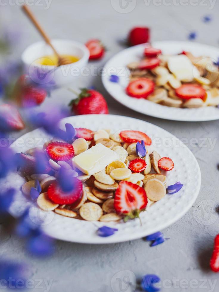 pannkakaflingor, trendig mat. mini spannmålspannkakor med smör, honung och jordgubbar. foto