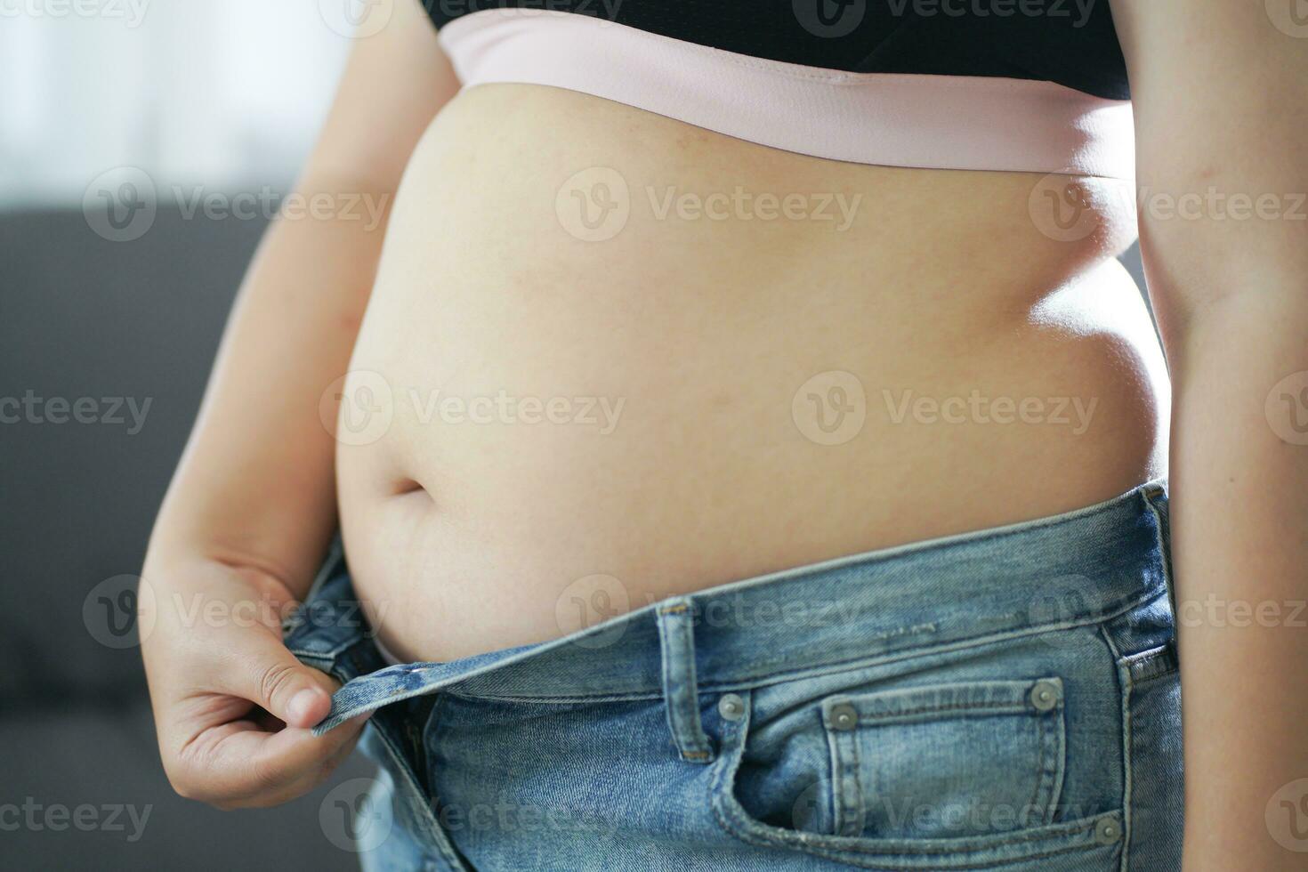 fet kvinna med fett upprörd handla om henne mage. övervikt kvinna rörande hans fett mage och vilja till tappa bort vikt. fett kvinna med tajt Kläder orolig handla om vikt diet livsstil begrepp foto