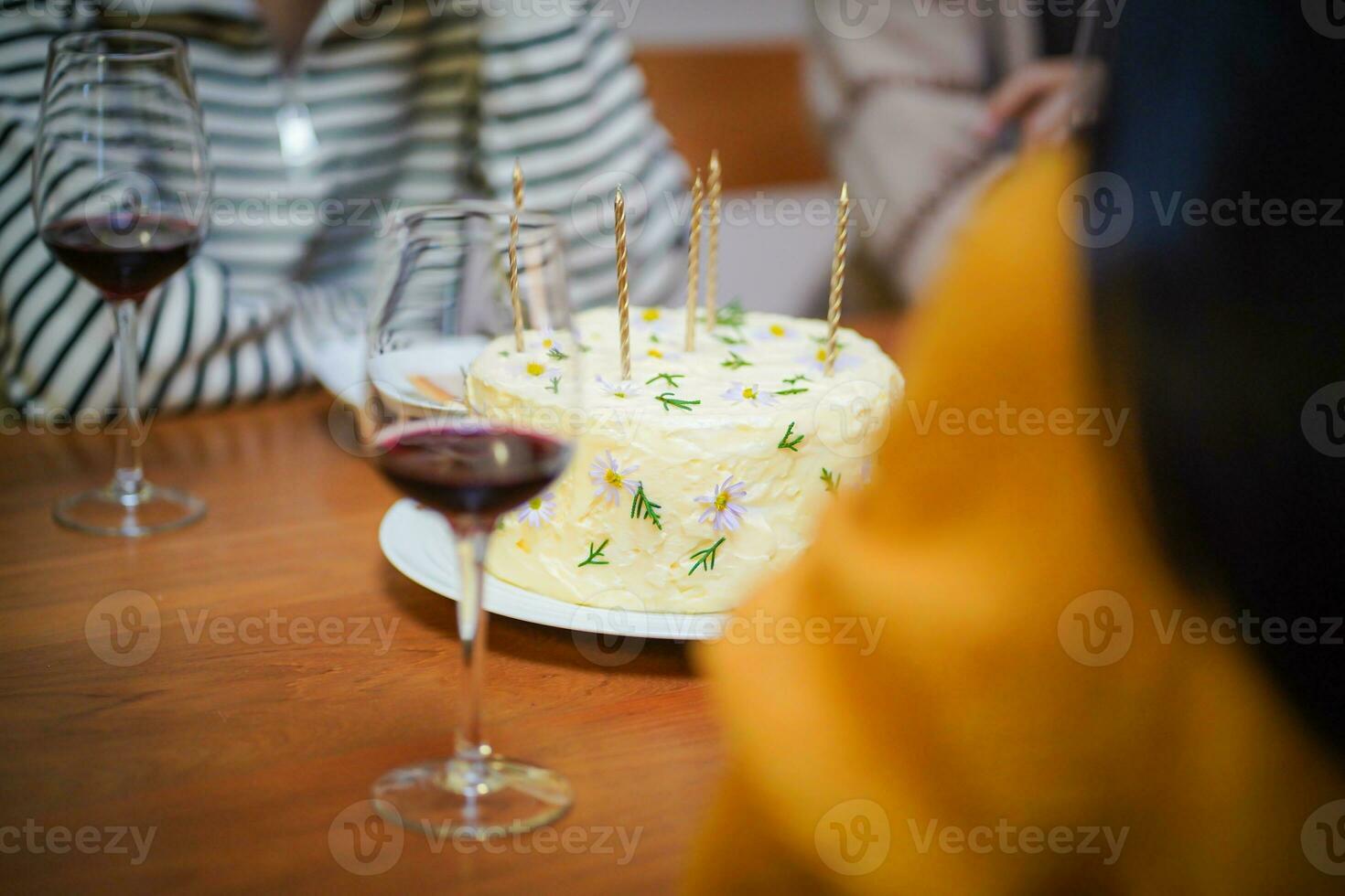 glad vänner njuter Hem födelsedag Semester fest. asiatisk syster glädjande dricka röd vin fira med födelsedag kaka foto