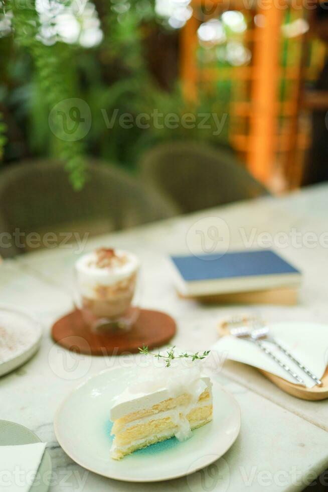 kokos kaka och kaffe i en Kafé på de fläck bakgrund. traditionell efterrätt skivad av utsökt kokos lager kaka foto