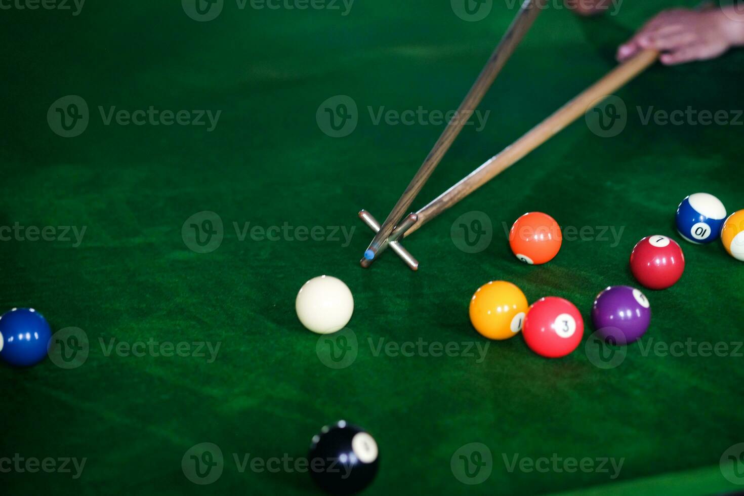mannens hand och kö ärm spelar snooker spel eller framställning siktar till skjuta slå samman bollar på en grön biljard tabell. färgrik snooker bollar på grön fris. foto